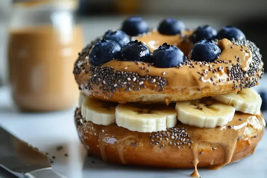 Blueberry bagel with peanut butter and banana slices in a home kitchen.